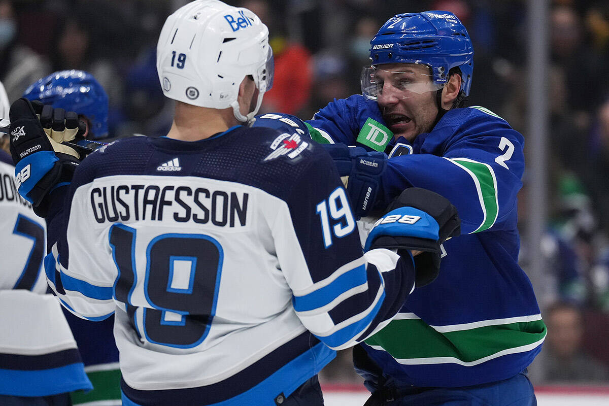Vancouver Canucks’ Luke Schenn, back right, shoves Winnipeg Jets’ David Gustafsson, of Sweden, during the second period of an NHL hockey game in Vancouver, on Saturday, Dec. 17, 2022. THE CANADIAN PRESS/Darryl Dyck