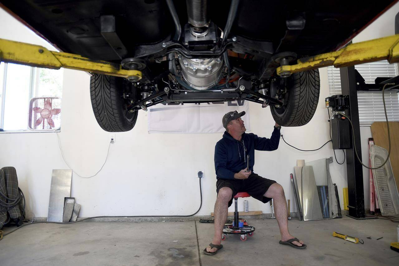 Pat Dailey, co-owner of Inspire EV, works on an electrified 1965 Ford Mustang in Arvada, Colo., on Sept. 23, 2022. Dailey is part of a small but expanding group of tinkerers, racers, engineers, and entrepreneurs across the country, converting vintage cars and trucks into greener, often much faster, electric vehicles. (AP Photo/Thomas Peipert)