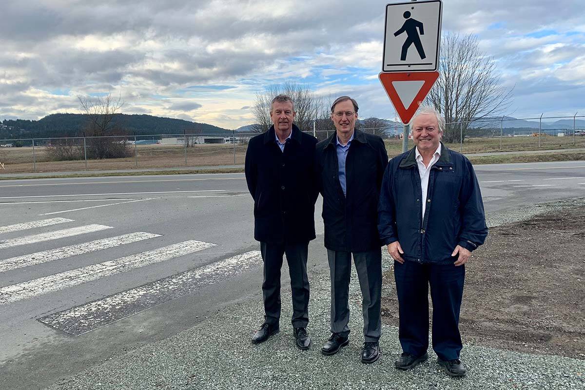 Geoff Dickson, president and chief executive officer of the Victoria International Airport, Sidney Mayor Cliff McNeil-Smith and North Saanich Mayor Peter Jones stand near the site of the proposed roundabout near the Amazon facility in Sidney. The three parties recently formalized their funding agreement for the $6.4 million project. (Town of Sidney/Submitted)
