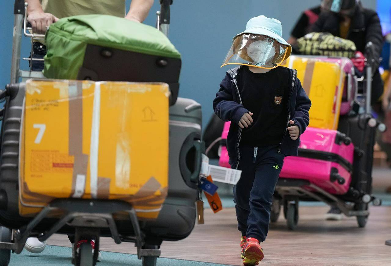 A young boy who arrived on a Cathay Pacific flight from Hong Kong wears a face mask and face shield at Vancouver International Airport, in Richmond, B.C., on Wednesday, Jan. 4, 2023. THE CANADIAN PRESS/Darryl Dyck