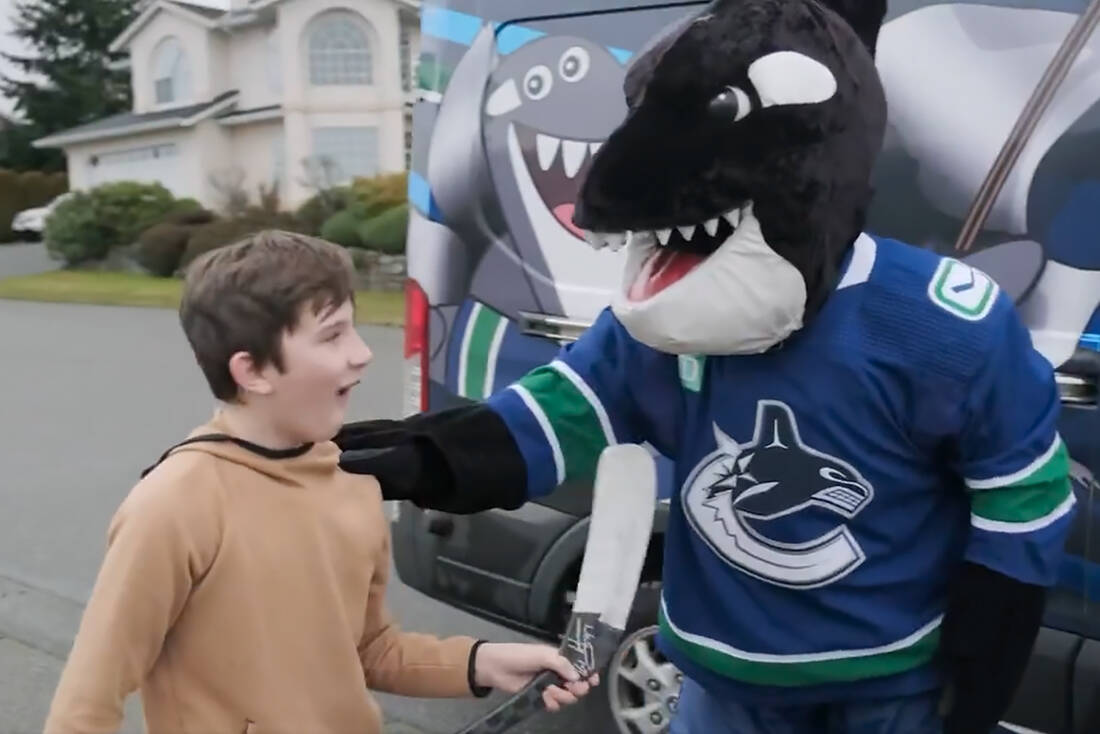 Nanaimo’s Linden Erwin is presented with a signed Bo Horvat hockey stick by Vancouver Canucks mascot Fin on Tuesday, Jan. 10, in Nanaimo. (Vancouver Canucks image)
