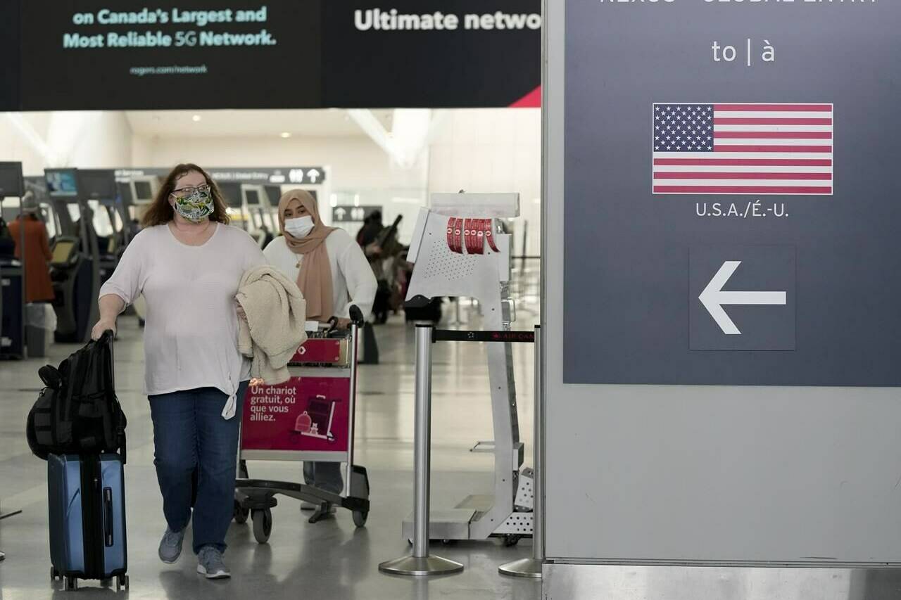 People travel to the United States of America at Pearson International Airport in Toronto, Friday, Dec. 3, 2021. Air Canada warned travellers to check their flights before heading to the airport as troubles caused by a key computer outage at the U.S. Federal Aviation Administration caused delays. THE CANADIAN PRESS/Nathan Denette