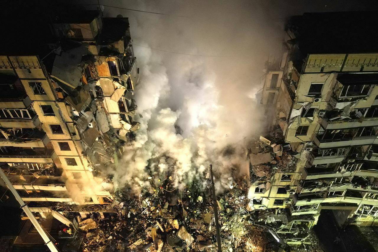 Emergency workers clear the rubble after a Russian rocket hit a multistory building leaving many people under debris in the southeastern city of Dnipro, Ukraine, Saturday, Jan. 14, 2023. (AP Photo/Evgeniy Maloletka)