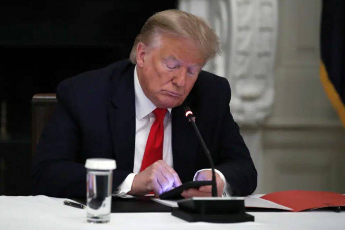 FILE - In this Thursday, June 18, 2020 file photo, President Donald Trump looks at his phone during a roundtable with governors on the reopening of America's small businesses, in the State Dining Room of the White House in Washington. On Wednesday, Jan. 25, 2023, Facebook parent Meta said in a blog post it is reinstating former President Trump’s personal account after two-year suspension following the Jan. 6 insurrection. (AP Photo/Alex Brandon, File)