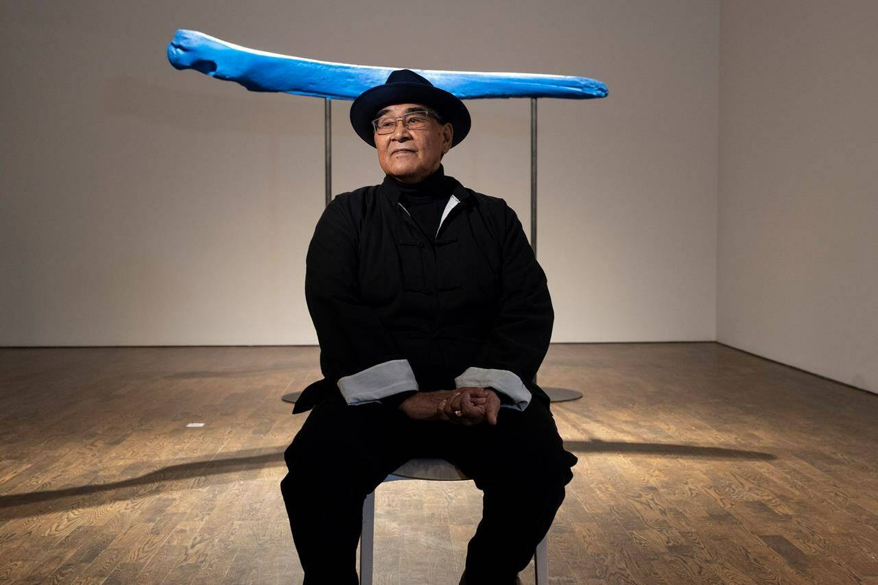 Inuvialuk sculptor David Ruben Piqtoukun sits in front of his piece entitled “Thar She Blows!” at the Art Gallery of Ontario in Toronto on Wednesday, Jan. 25, 2023, ahead of his exhibition “Radical Remembrance: The Sculptures of David Ruben Piqtoukun.” THE CANADIAN PRESS/Chris YoungC