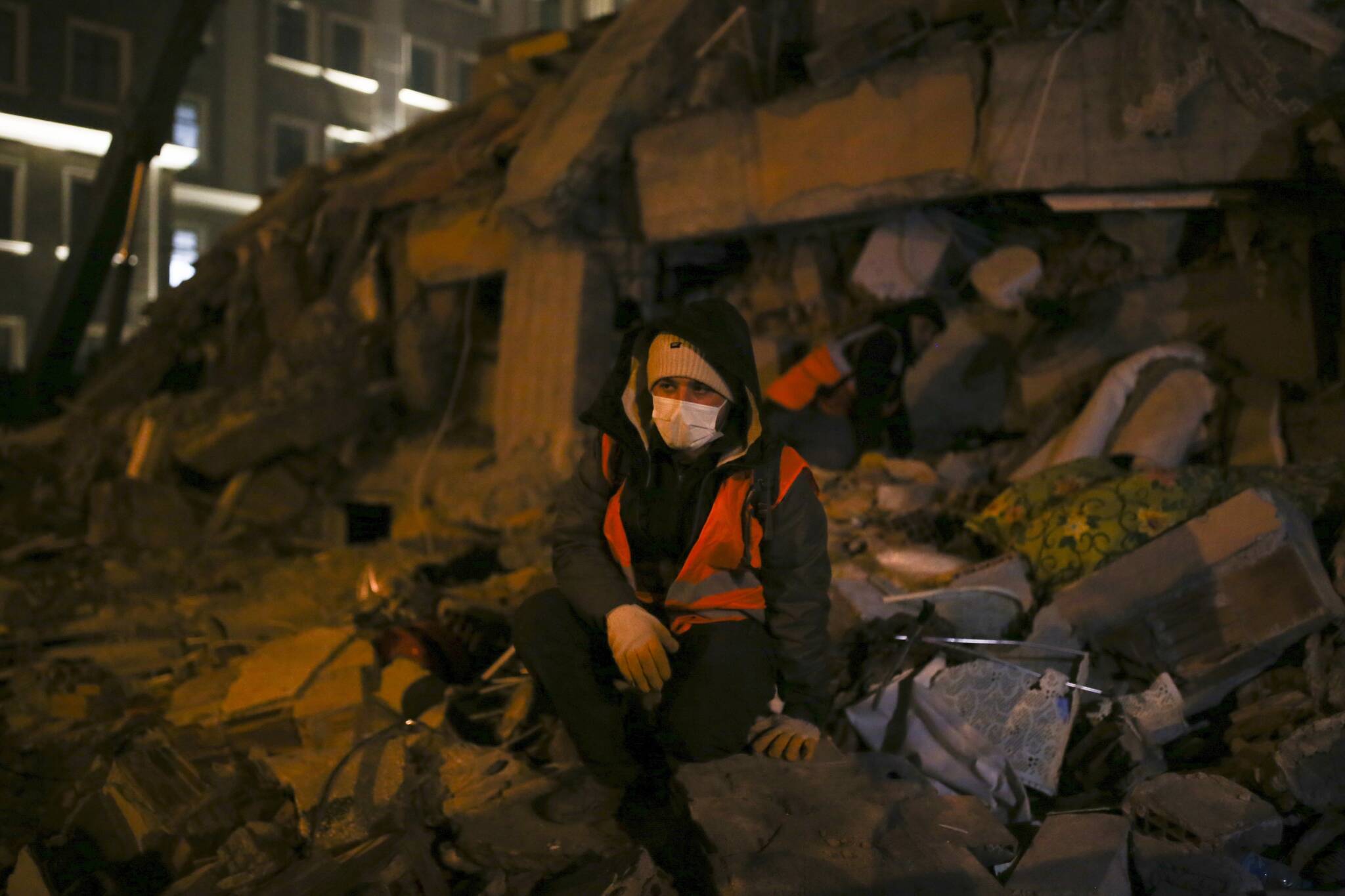 A man sits in front of a destroyed building, in Adiyaman, southeastern Turkey, Wednesday, Feb. 8, 2023. With hope of finding survivors fading, stretched rescue teams in Turkey and Syria searched Wednesday for signs of life in the rubble of thousands of buildings toppled by the world’s deadliest earthquake in more than a decade. (AP Photo/Emrah Gurel)
