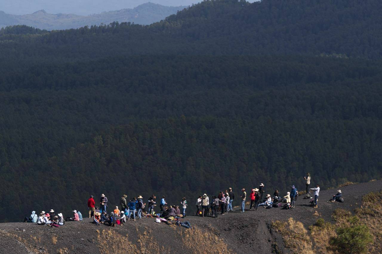 A group belonging to an international vulcanology congress rest on the crater lip of the Paricutin volcano, in Mexico, Wednesday, Feb. 22, 2023. The crater of the volcano is about 200 meters across and it is possible to both climb the volcano and walk around the entire perimeter. (AP Photo/Eduardo Verdugo)