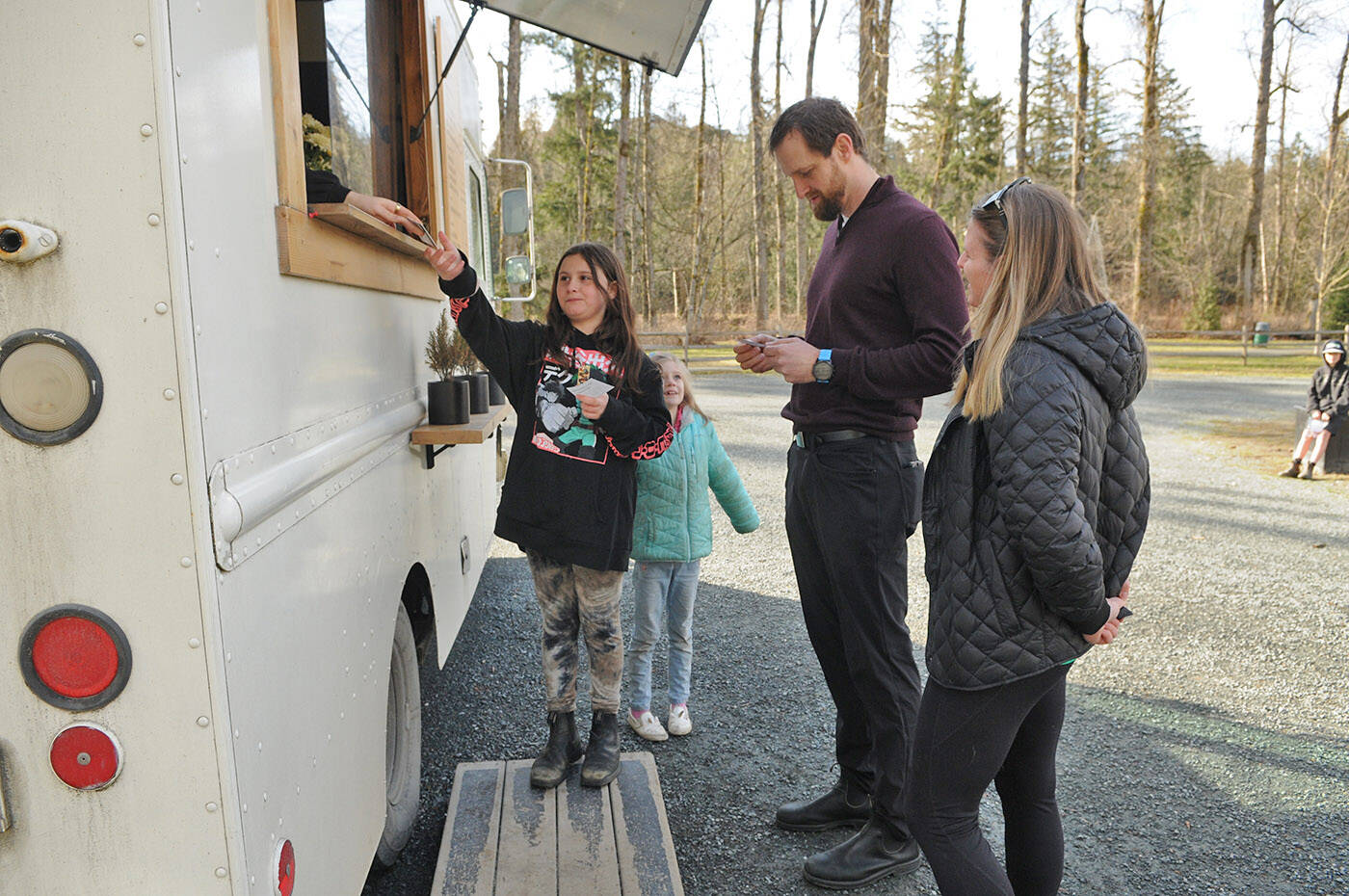 Harlow Montroy (black sweatshirt) and Summer Hamper (turquoise coat) from Watson Elementary buy coffee for two strangers at Vedder Park during Watson Elementary’s Kindness Project on Wednesday, March 15. For more photos, go to theprogress.com/community (Jenna Hauck/ Chilliwack Progress)