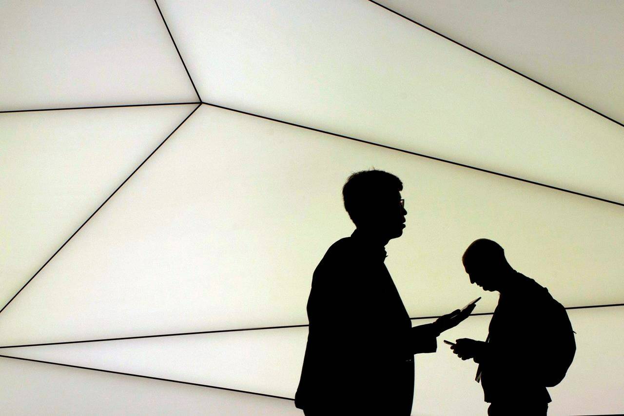 Attendants hold their devices as they walk during the Mobile World Congress wireless show in Barcelona, Spain, Monday, Feb. 27, 2017. A federal source says the coming budget will detail how the Liberals plan to go after hidden or unexpected consumer fees, following the United States announcing its own crackdown on these charges. THE CANADIAN PRESS/AP, Emilio Morenatti