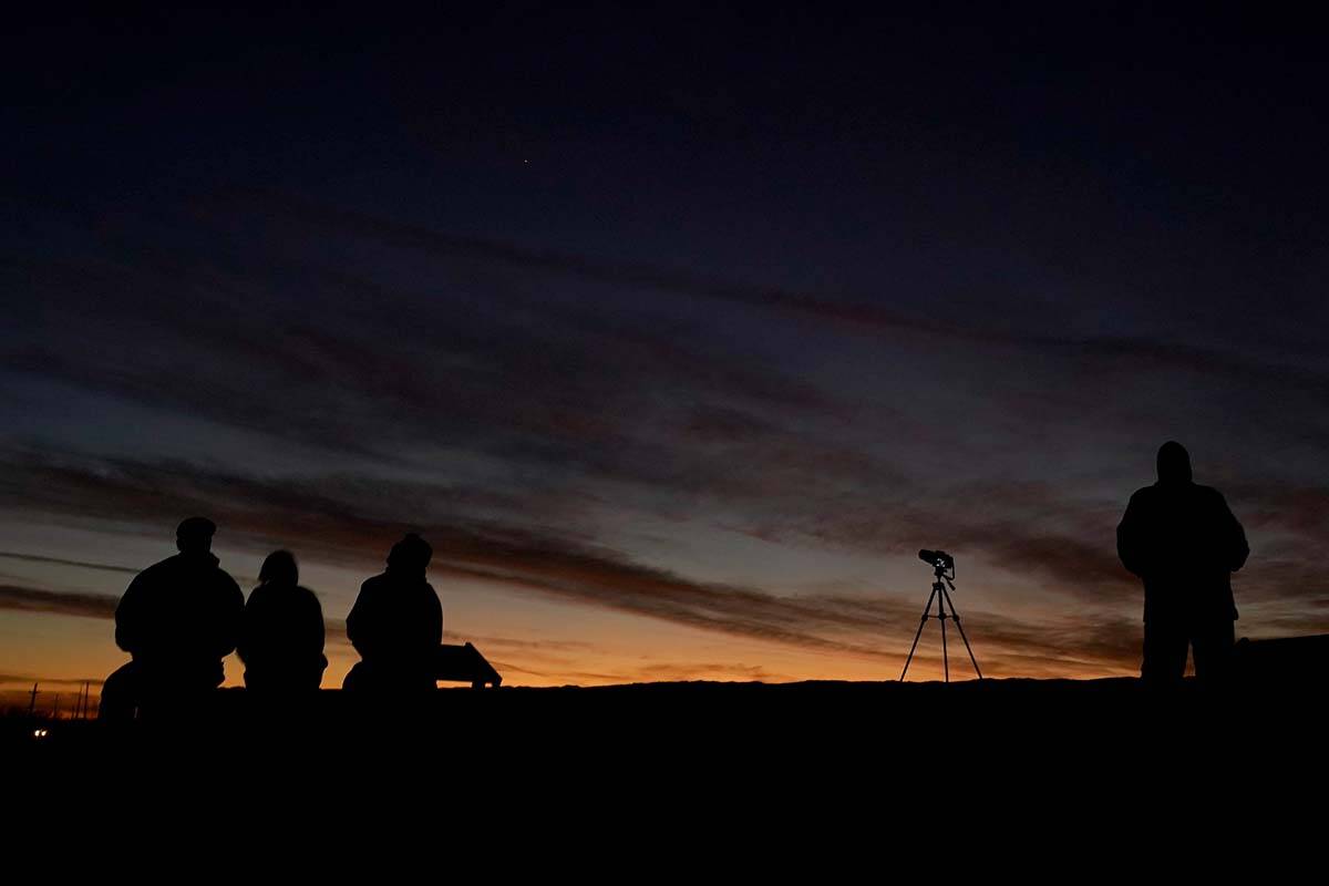 People are silhouetted against the sky at dusk as they watch the alignment of Saturn and Jupiter, Monday, Dec. 21, 2020, in Edgerton, Kan. (AP Photo/Charlie Riedel)