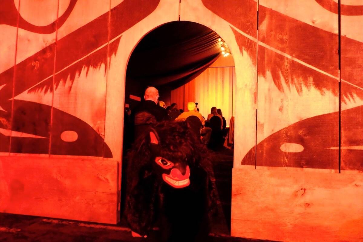 A black bear pops its head out of the longhouse door during the March 22 performance of naaʔuu. (Nora O’Malley photo)