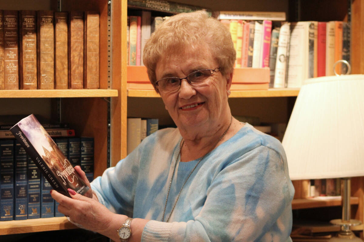 Local author Valerie Green holds a copy of her first historical fiction book, called Providence, inside her home library in Saanich. (Austin Westphal/News Staff)