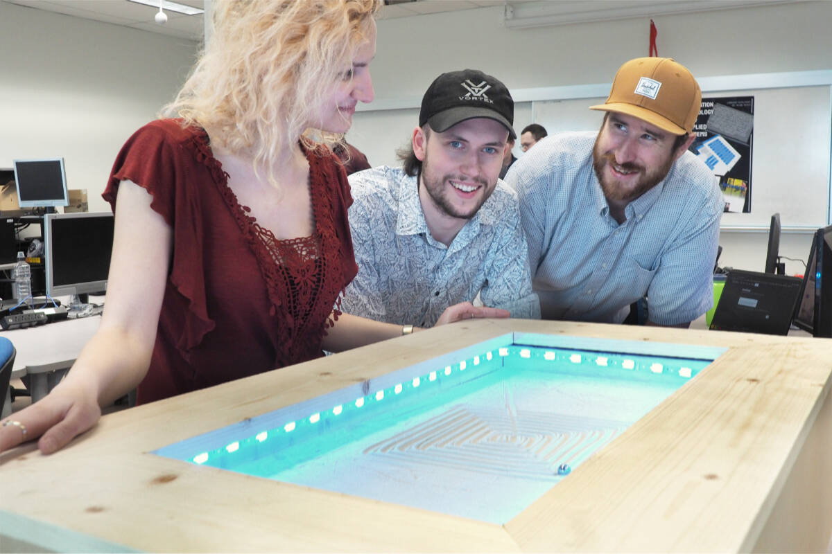 Diana Ied, Silas Boom and Nathan Singleton demonstrate their kinetic sand table, a prototype for a coffee table that uses a magnetically driven ball bearing to draw artistic patterns in sand. (Chris Bush/News Bulletin)