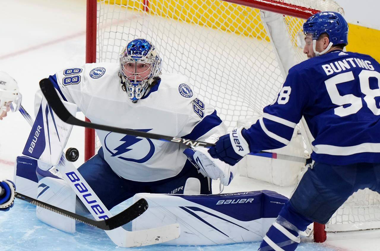 Tampa Bay Lightning goaltender Andrei Vasilevskiy (88) watches the puck closely as Toronto Maple Leafs left wing Michael Bunting (58) tries to get his stick on it during second period NHL Stanley Cup playoff hockey action in Toronto, on Tuesday, April 18, 2023. Bunting received a match penalty for an illegal check to head on Tampa Bay Lightning defenceman Erik Cernak in Game 1 of the NHL playoff series. THE CANADIAN PRESS/Frank Gunn