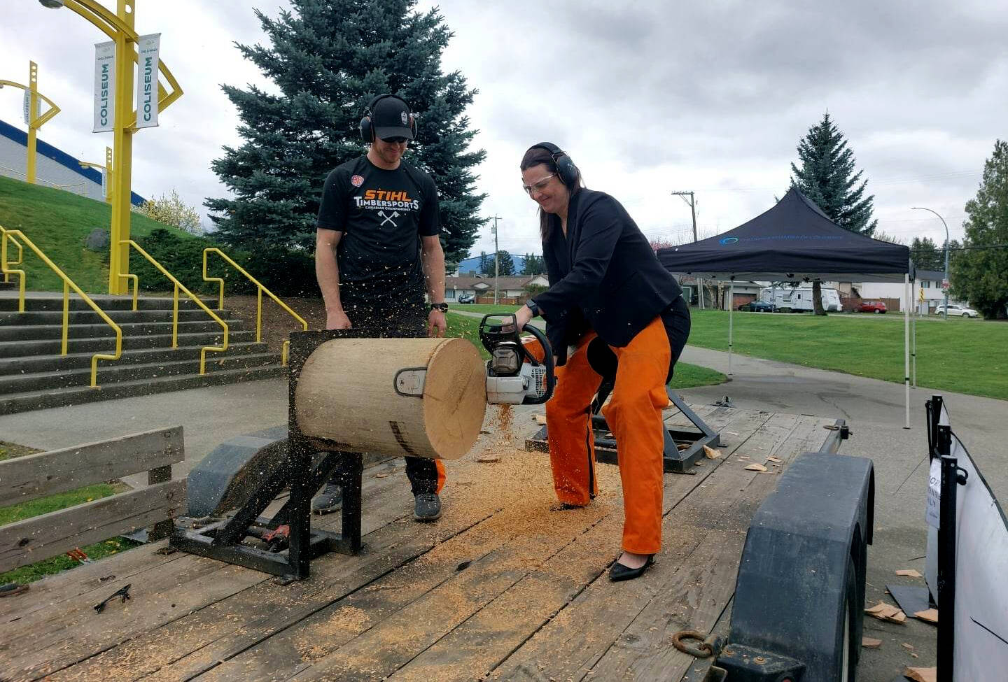 With Stihl Timbersports athlete Stirling Hart watching, Chilliwack Chamber of Commerce executive director Leanna Kemp fires up a chainsaw and cuts through a log. Hart was in town Monday to promote the Stihl Timbersports National Championship, which is coming to Chilliwack Aug. 12-13, 2023. (Eric J. Welsh/ Chilliwack Progress)