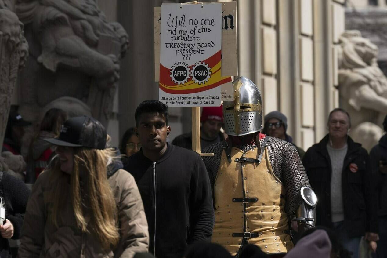 A Public Service Alliance of Canada member wearing a suit of armour walks the picket line outside the Prime Minister’s Office, Thursday, April 27, 2023 in Ottawa. Workers in Canada’s largest federal public service union are hitting the picket lines for the 10th day as negotiations between the federal government and union continue. THE CANADIAN PRESS/Adrian Wyld