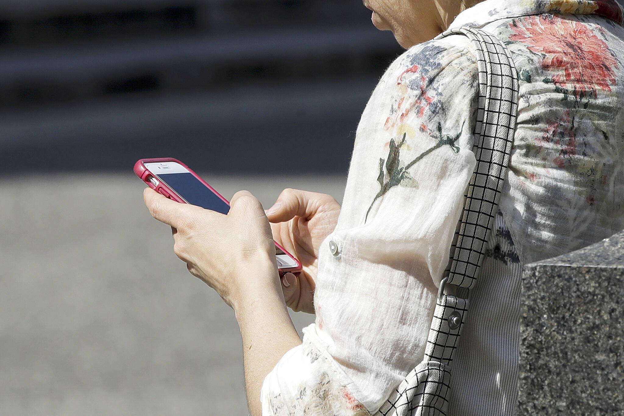 FILE - In this April 8, 2019, file photo, a woman browses her smartphone in Philadelphia. (AP Photo/Matt Rourke, File)