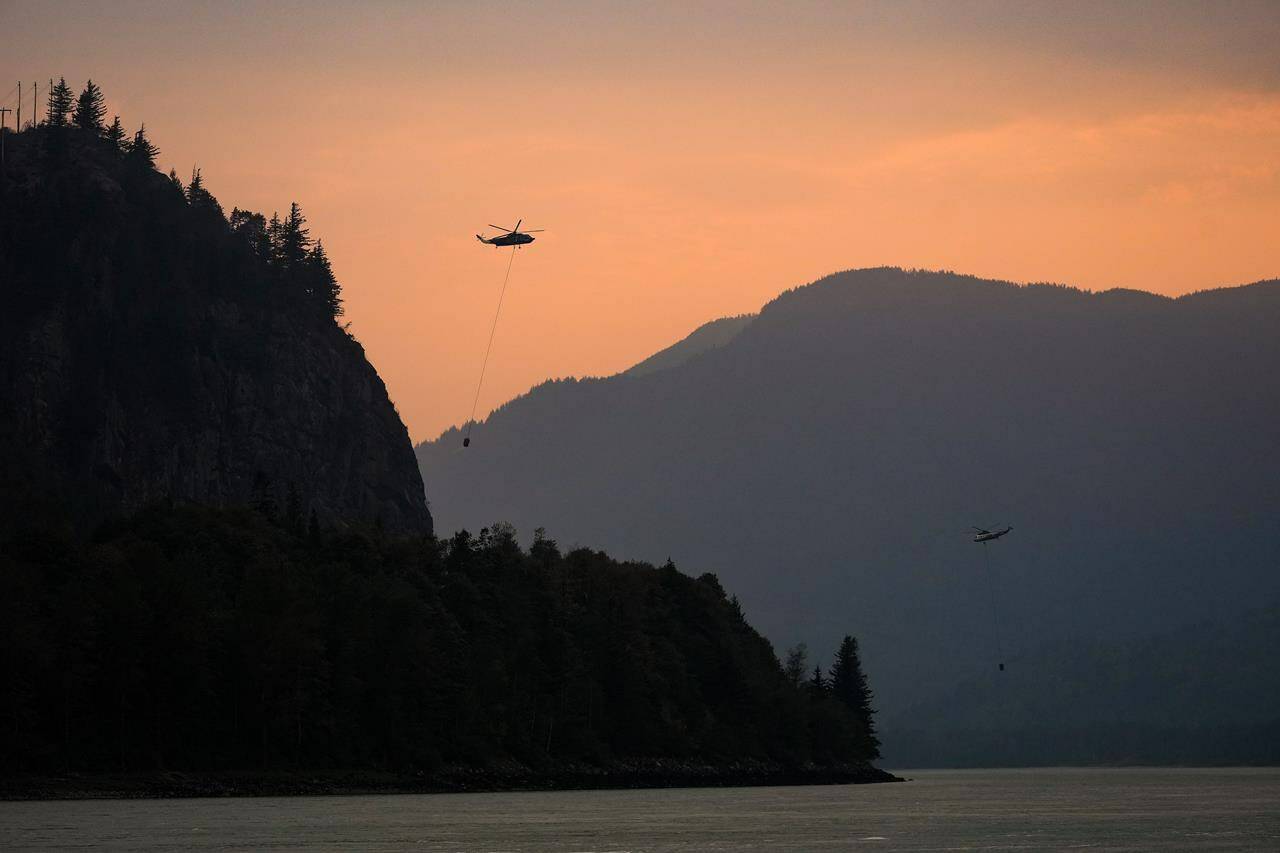 Helicopters with water buckets battling the Flood Falls Trail wildfire pick up water from the Fraser River, in Hope, B.C., Monday, Sept. 12, 2022. Environment Canada says smoke from wildfires in the B.C. Interior is expected to worsen in the coming days, bringing poor air quality and associated health risks. THE CANADIAN PRESS/Darryl Dyck