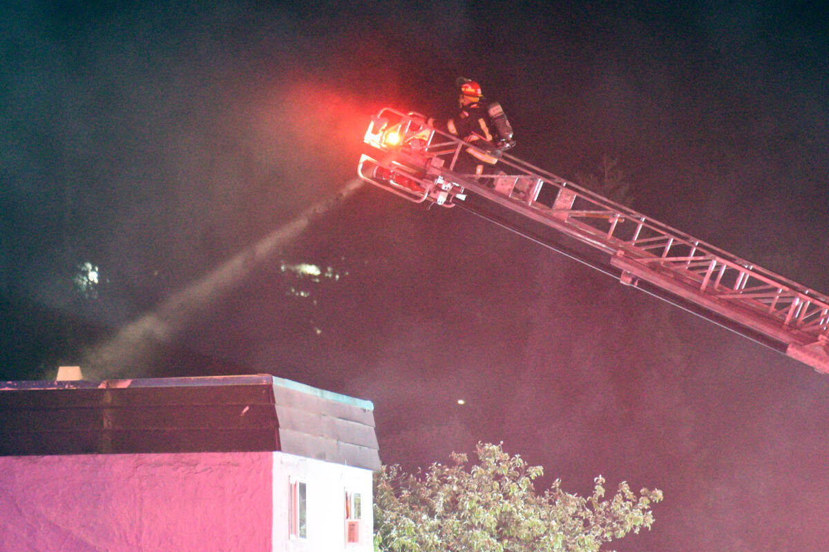 A firefighter with Port Alberni Fire Dept. shines a light from the aerial ladder onto the roof of the Wintergreen Apartment building on Fourth Avenue after one of the upper units caught fire late Thursday, May 18, 2023. (SUSAN QUINN/ Alberni Valley News)