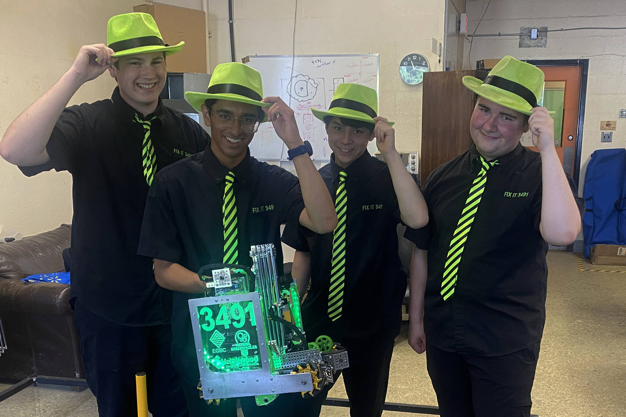 FIX IT members Max Gregg, Armen Kareer, Bryce Kong and Garrett Waddell tip their neon fedoras as they prepare to take on the world in a robotics competition. (Ella Matte/News Staff)