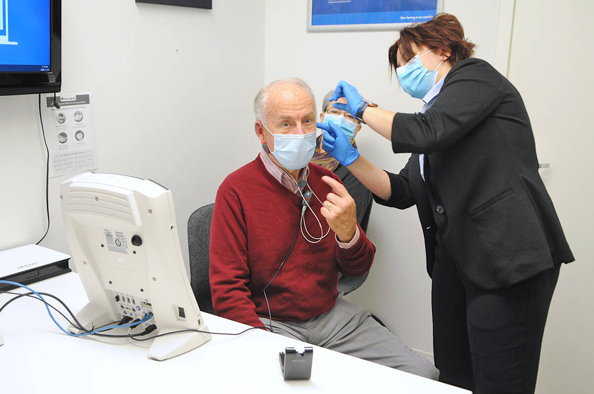 Sarah Ploj with HearingLife fits Brian Preston with his first hearing aid as wife, Rosemary, watches on Friday, Nov. 20, 2020 (Jenna Hauck/ Chilliwack Progress)