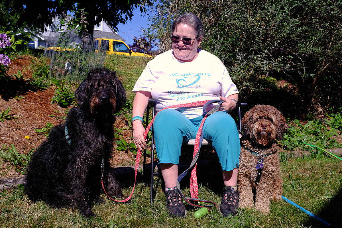 Linda MacMullen, who has been battling myasthenia gravis for more than two decades, poses with her two support dogs, Sierra (left) and Bailey. (Olivier Laurin / Comox Valley Record)