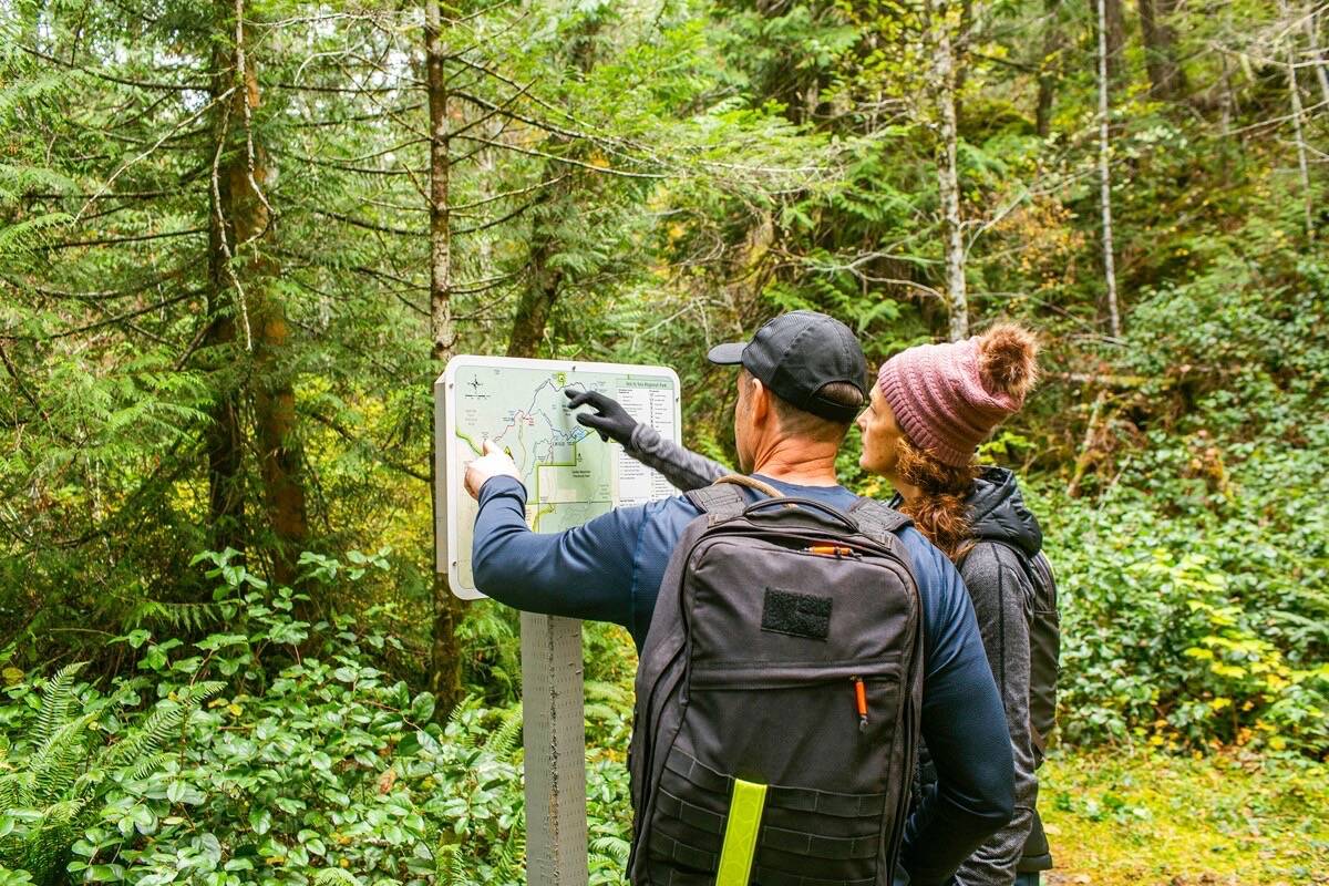 Hikers check the official Capital Regional District park map during a hike in Sea to Sea Regional Park in Sooke. This summer the CRD reminds park visitors to follow simple park etiquette such as staying on official, sanctioned trails. (Courtesy CRD Parks)