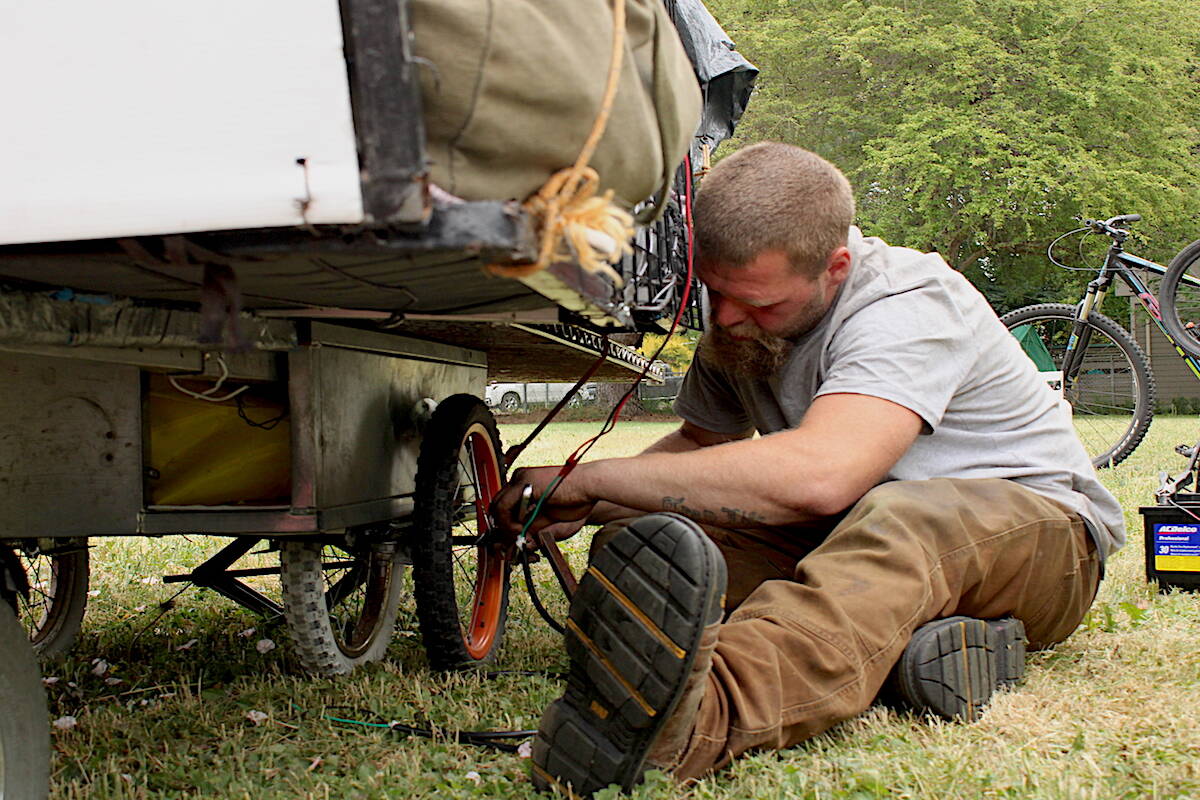 Cody (C.J.) Poole works on the solar-powered cart that’s been his home for months. He and others are hoping to build versions of the carts for their homeless friends living with physical disabilities. (Jake Romphf/News Staff)