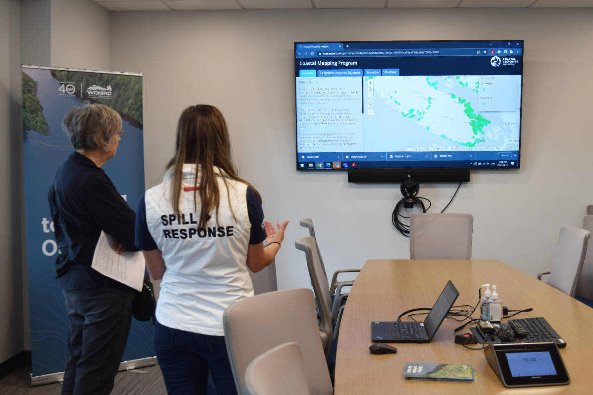 A WCMRC employee shows a visitor the company’s Coastal Mapping Program, which identifies at-risk areas before a spill occurs. (ELENA RARDON / Alberni Valley News)