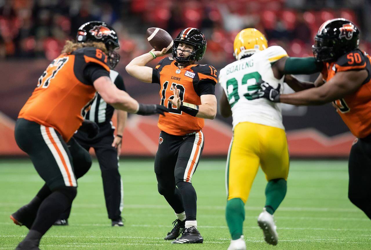 B.C. Lions quarterback Nathan Rourke (12) passes as Phillip Norman (50) holds off Edmonton Elks’ Kwaku Boateng (93) during the first half of a CFL football game in Vancouver, on Friday, November 19, 2021. The Lions say they have cancelled the team’s practice on Wednesday after offensive lineman Norman suffered what they described as a “significant medical episode.” THE CANADIAN PRESS/Darryl Dyck