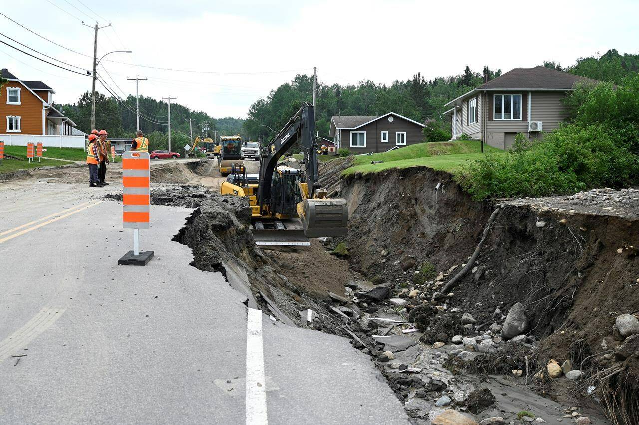 Crews begin repairs to a washed-out section of Highway 170 in Rivière-Éternité, Que., Sunday, July 2, 2023. The search for two people swept away by a landslide in Quebec’s Saguenay-Lac-St-Jean region is stretching into a third day. THE CANADIAN PRESS/Jacques Boissinot