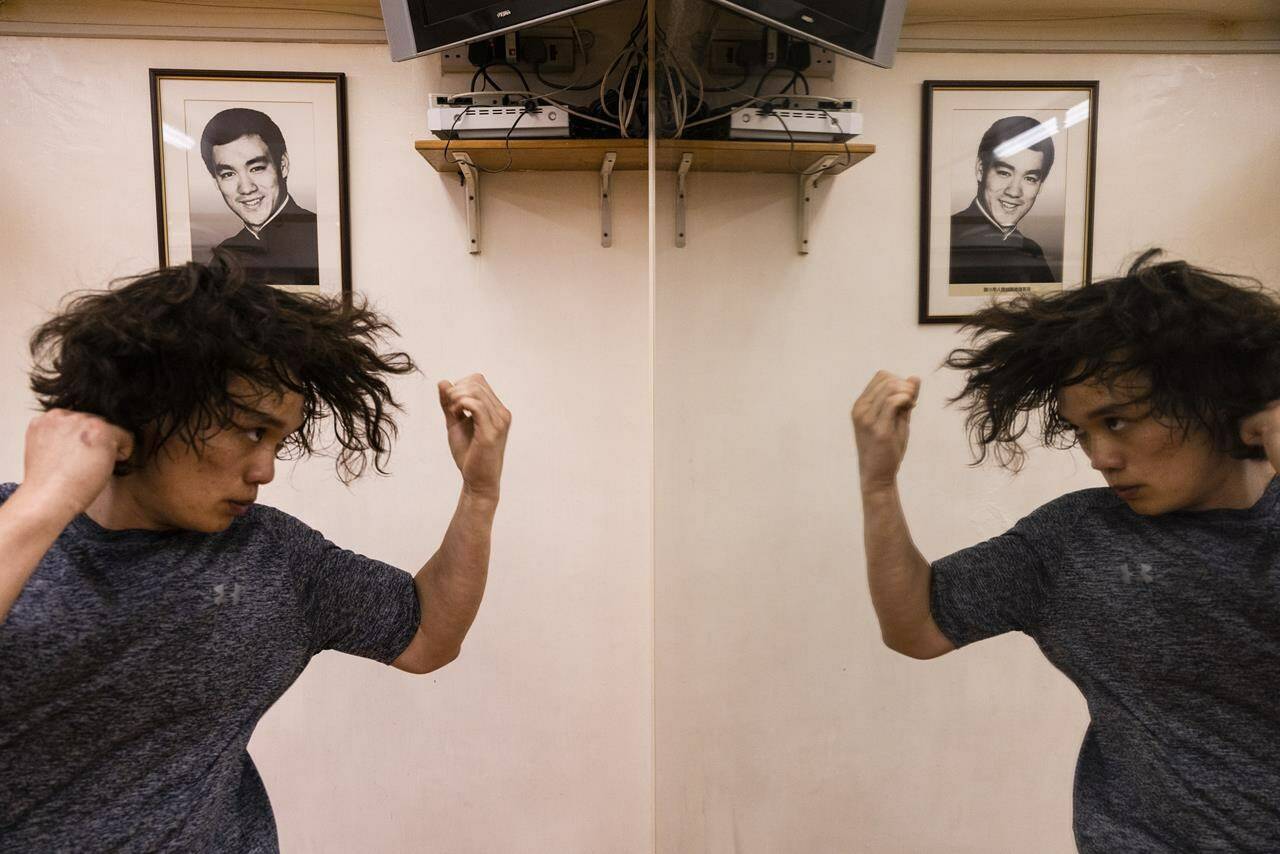 A practitioner trains in front of a photo of Bruce Lee during a Jeet Kune Do class in Hong Kong, Wednesday, July 19, 2023. (AP Photo/Louise Delmotte)