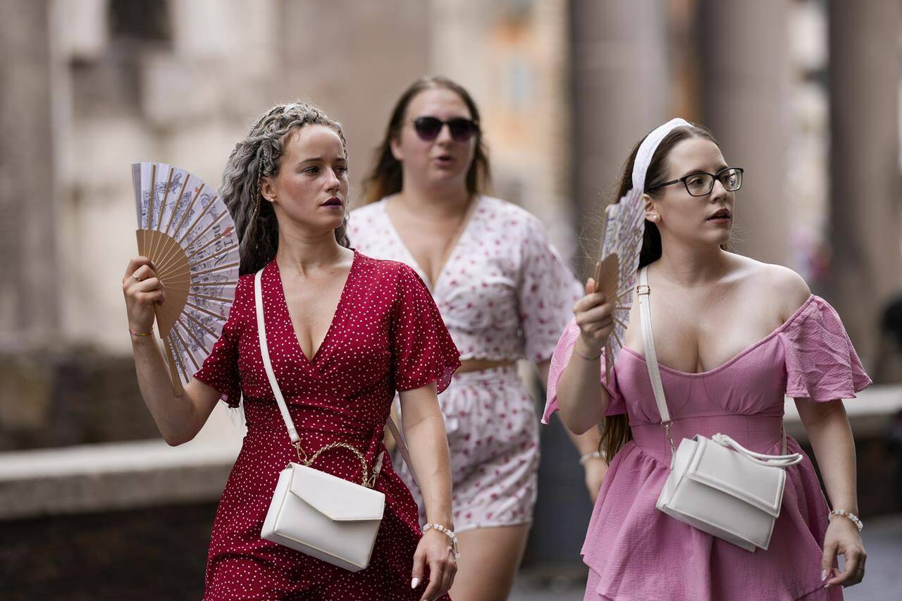 FILE - Tourists use foldable fans to cool off as they visit Rome, Saturday, July 22, 2023. Rising global temperatures are elevating air conditioning from a luxury to a necessity in many parts of Europe, which long has had a conflictual relationship with energy-sucking cooling systems deemed by many a U.S. indulgence. (AP Photo/Andrew Medichini, file)
