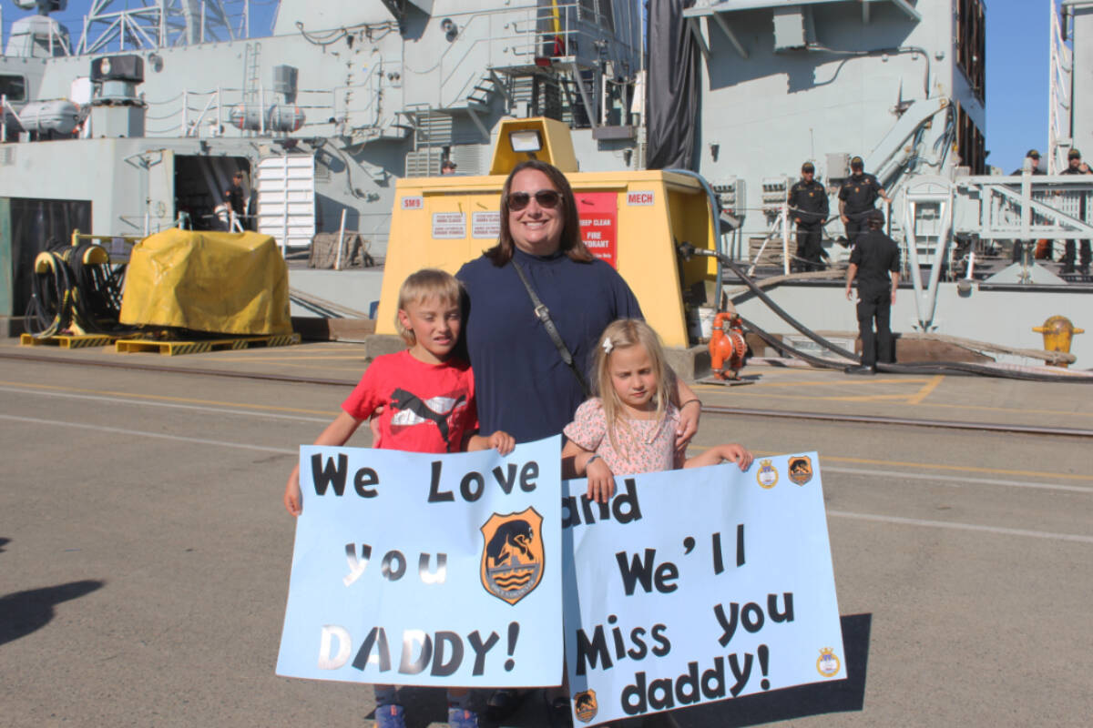 Wife, mother and Petty Officer 2nd Class Andrea Chabassol with her children and their signs in front of the HMCS Vancouver. (Ella Matte/News Staff)