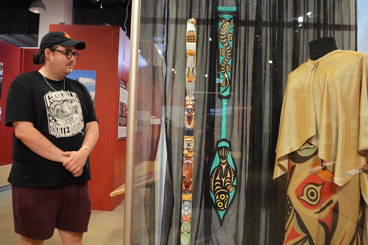 Coast Salish visual artist and storyteller, Eliot White-Hill, looks onto a display case featuring work by William Good, Joel Good and Ay Lelum as part of the ‘What is Sacred?’ exhibit that he curated for the Nanaimo Museum. (Mandy Moraes/News Bulletin)