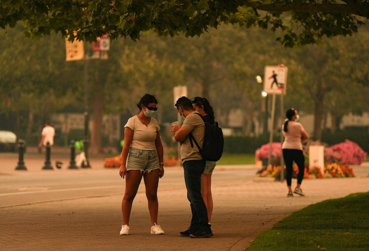 People wear masks due to poor air quality as smoke from the McDougall Creek wildfire fills the air in Kelowna, B.C., Friday, Aug. 18, 2023. THE CANADIAN PRESS/Darryl Dyck