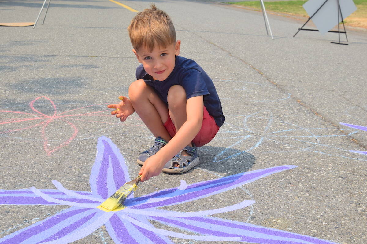 Rafael Garcia-Laboviti paints a camas flower on the mural on Saanich’s Falaise Crescent. (Brendan Mayer/News Staff)