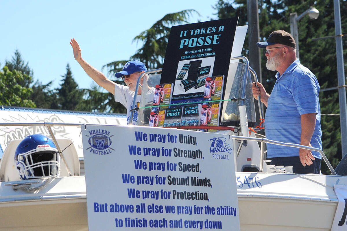 Joe Martino, left, and Jim Lynch of the Ballenas Whalers Football Society introduces the book ‘It Takes a Posse’ at the Canada Day Parade. Martino and his son Chris authored the book about the history of football in Parksville Qualicum Beach and also recently published their second book, ‘Down By Six’. (Michael Briones photo)