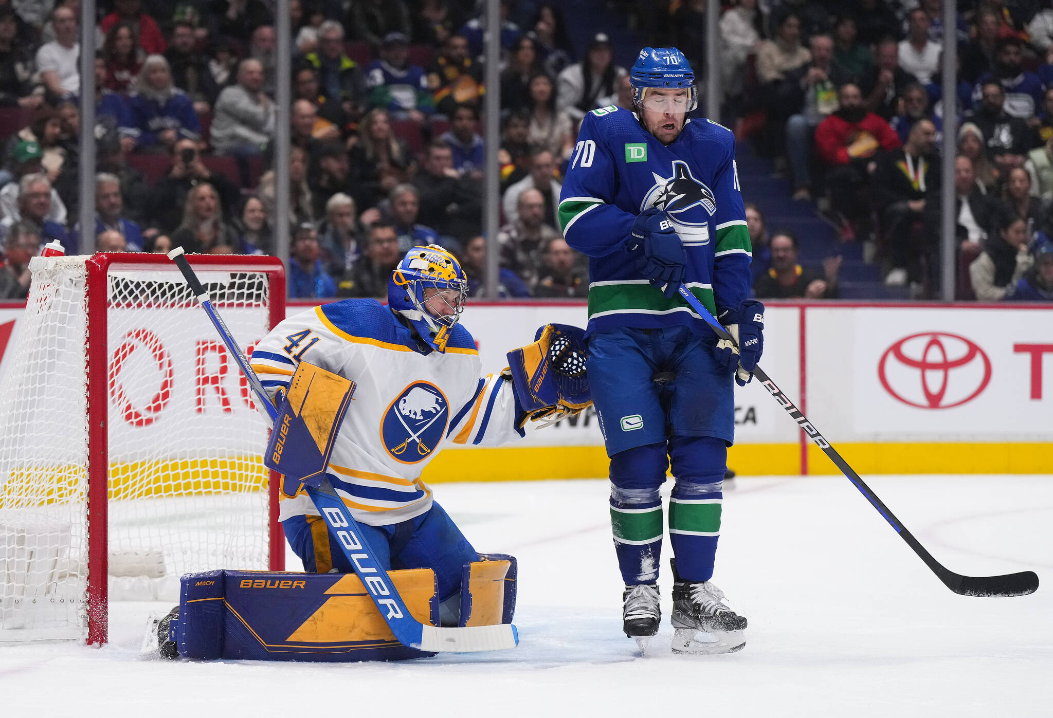 Vancouver Canucks’ Tanner Pearson, right, is struck in the groin by the puck as he stands in front of Buffalo Sabres goalie Craig Anderson during the first period of an NHL hockey game in Vancouver, on Saturday, October 22, 2022. THE CANADIAN PRESS/Darryl Dyck