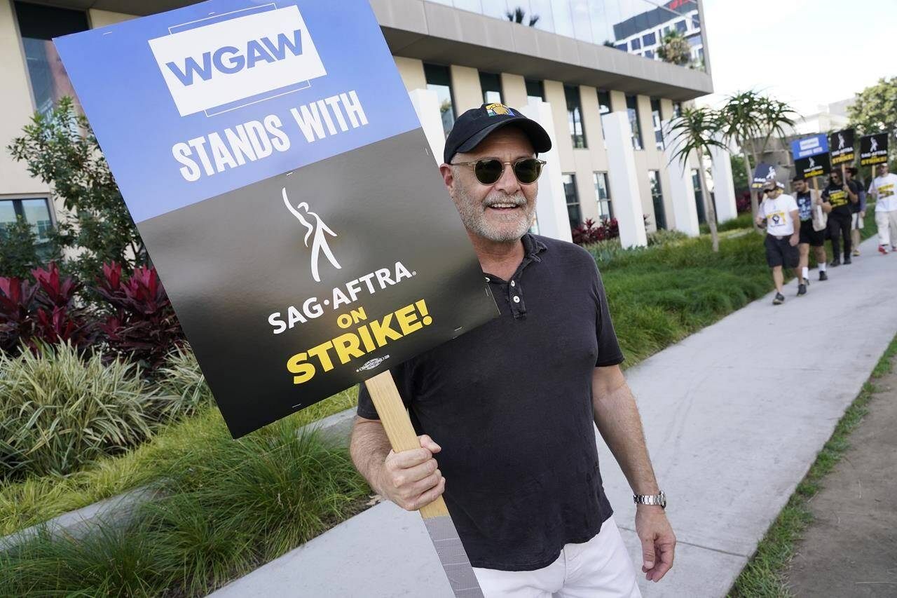Writer Matthew Weiner carries a sign on the picket line outside Netflix on Wednesday, Sept. 27, 2023, in Los Angeles. Hollywood’s writers strike was declared over Tuesday night when board members from their union approved a contract agreement with studios, bringing the industry at least partly back from a historic halt in production. The actors strike continues in their bid to get better pay and working conditions. (AP Photo/Chris Pizzello)