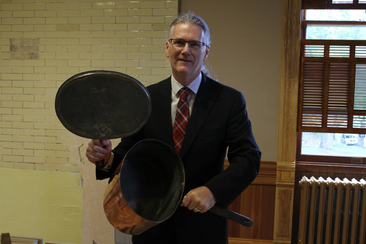 Craigdarroch Castle executive director John Hughes holds up an old pot and lid in the newly restored Dunsmuir-era kitchen. (Ella Matte/News Staff)