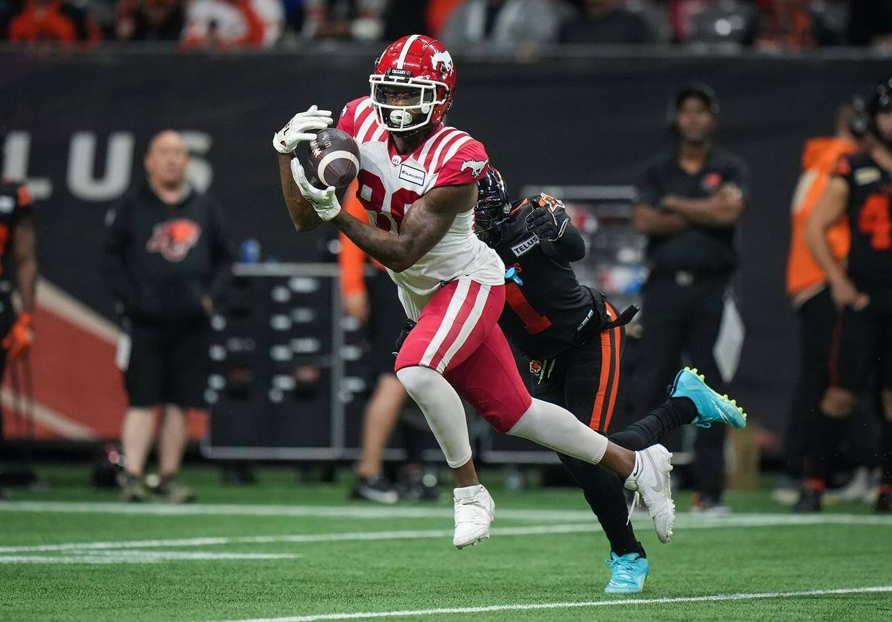 Calgary Stampeders' Tre Odoms-Dukes, front, makes a reception as B.C. Lions' Garry Peters defends during the first half of a CFL football game, in Vancouver, on Friday, October 20, 2023. THE CANADIAN PRESS/Darryl Dyck