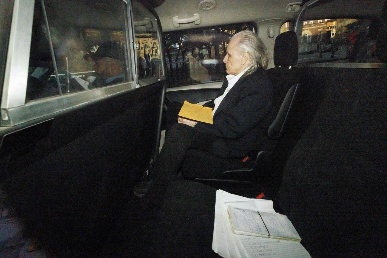 Seen through a police vehicle window, Peter Nygard arrives to a Courthouse in Toronto, Tuesday, Oct. 3, 2023, to attend his trial, accused of five counts of sexual assault and one count of forcible confinement in alleged incidents ranging from the 1980s to mid-2000s. THE CANADIAN PRESS/Cole Burston
