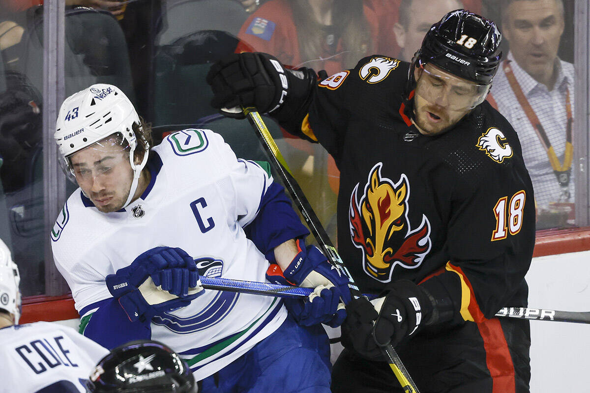 Vancouver Canucks defenceman Quinn Hughes, left, is checked by Calgary Flames forward A.J. Greer during third period NHL hockey action in Calgary, Thursday, Nov. 16, 2023.THE CANADIAN PRESS/Jeff McIntosh