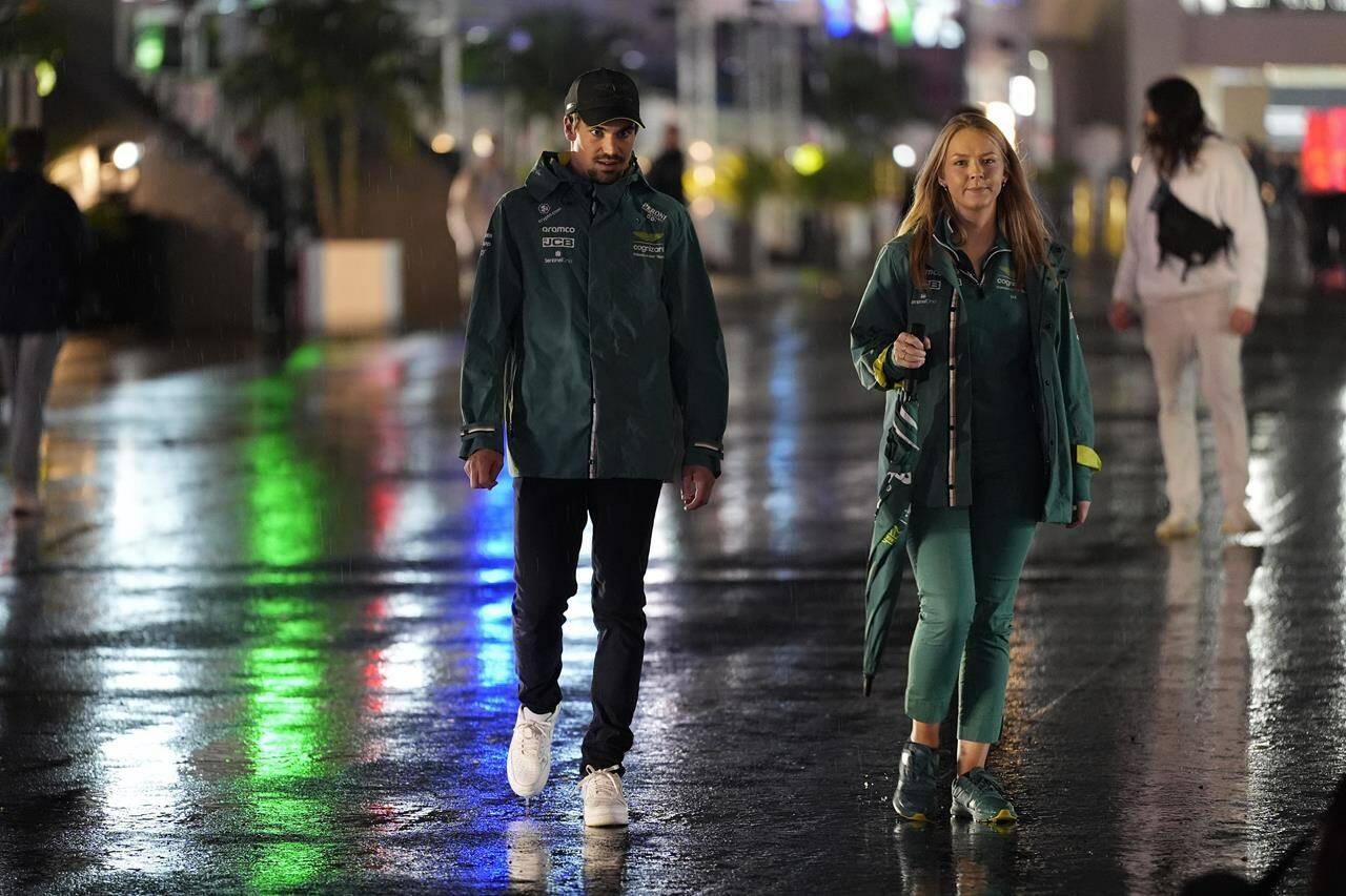 Aston Martin driver Lance Stroll, left, of Canada, walks in the rain to a media interview ahead of the Formula One Las Vegas Grand Prix auto race, Wednesday, Nov. 15, 2023, in Las Vegas. (AP Photo/Nick Didlick)