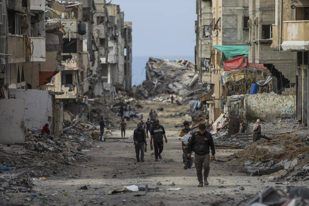 Palestinians walk through destruction in Shati refugee camp on Saturday, Nov. 25, 2023. on the second day of the temporary ceasefire between Hamas and Israel. (AP Photo/Mohammed Hajjar)