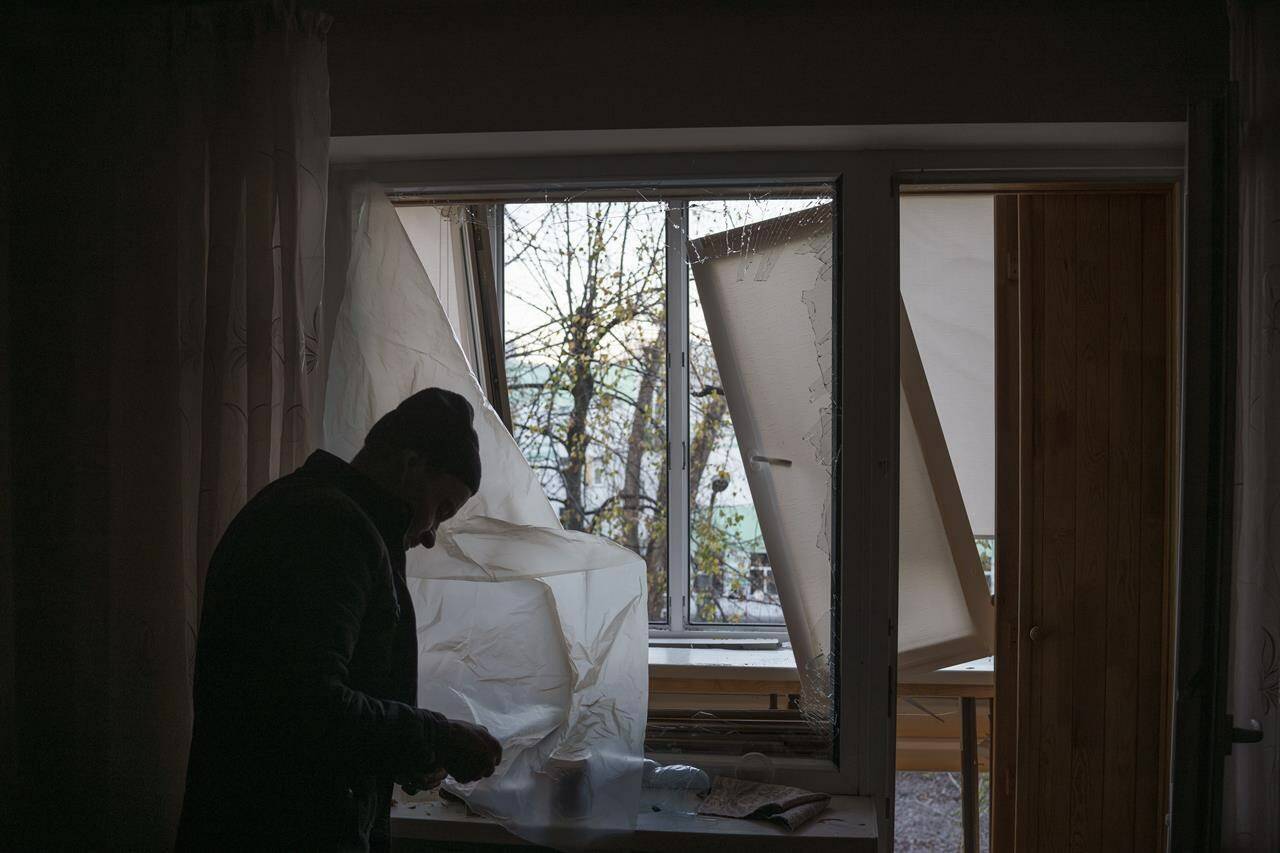 FILE - A man uses plastic to cover a broken window in his apartment following a Russian drone attack in Kyiv, Ukraine, Saturday, Nov. 25, 2023. On Monday, Dec. 4, the Biden Administration sent Congress an urgent warning about the need to approve tens of billions of dollars in military and economic assistance to Ukraine, saying that Kyiv’s war effort to defend itself from Russia’s invasion may grind to a halt without it. (AP Photo/Felipe Dana, File)