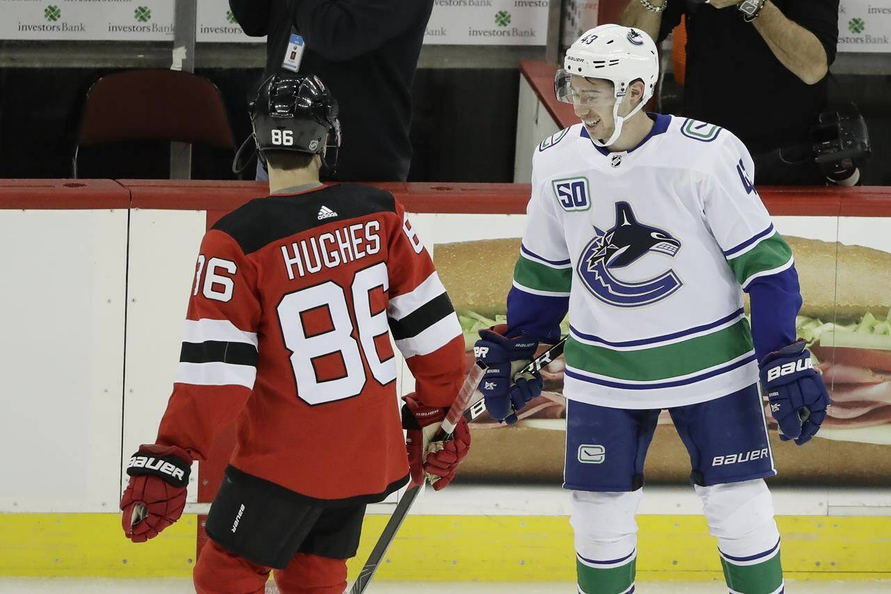 FILE - Vancouver Canucks’ Quinn Hughes, right, talks to his brother New Jersey Devils’ Jack Hughes, left, before of an NHL hockey game Saturday, Oct. 19, 2019, in Newark, N.J. There are 20 sets of brothers that have played in the league this season. (AP Photo/Frank Franklin II, File)