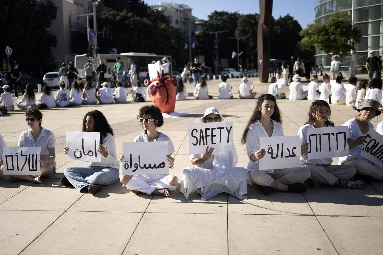 Women hold placards in Arabic, Hebrew, and English during a demonstration by Israeli and Palestinian women calling for peace, in Tel Aviv, Israel, Friday, Dec. 15, 2023. (AP Photo/Maya Alleruzzo)
