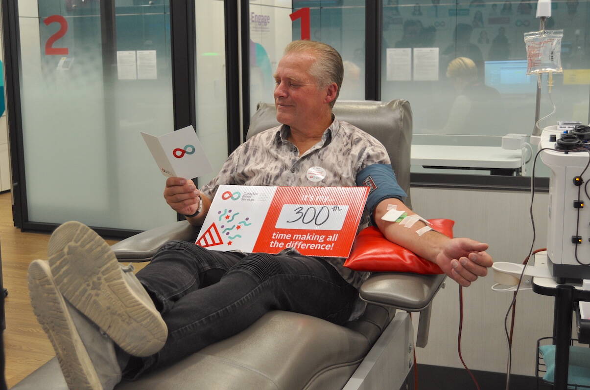 Longtime blood donor Peter Teschner reads a card of appreciation from Canadian Blood Services while giving his 300th donation. (Black Press Media file photo)